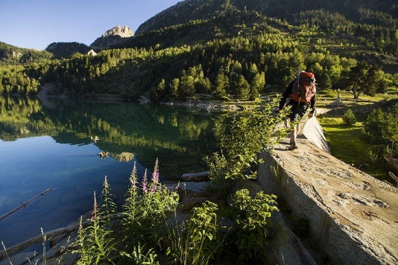 un hombre con una mochila camina sobre una roca junto a un lago