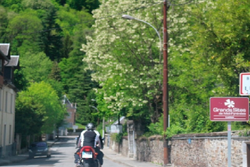 un hombre monta una motocicleta por una calle con una señal que dice grands sites