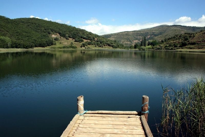 a wooden dock in the middle of a lake with mountains in the background