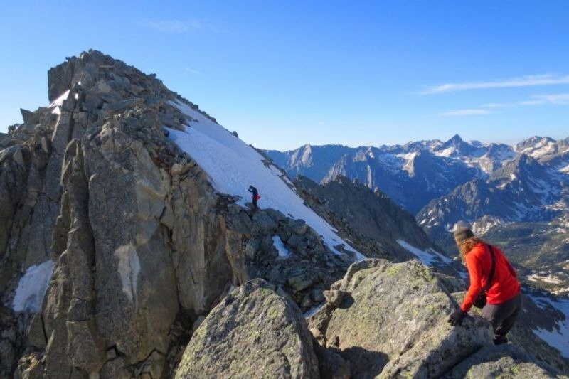una mujer en una chaqueta roja se encuentra en la cima de una montaña