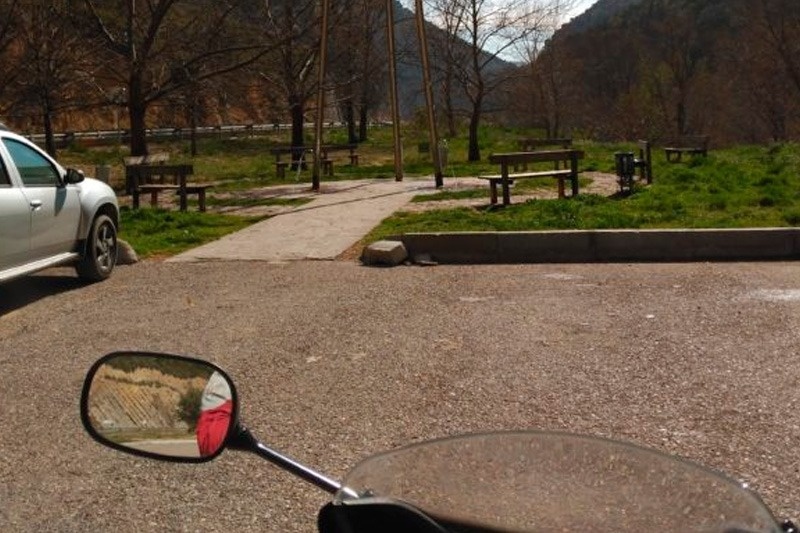un rétroviseur d' une moto montre un parc avec des bancs et des arbres