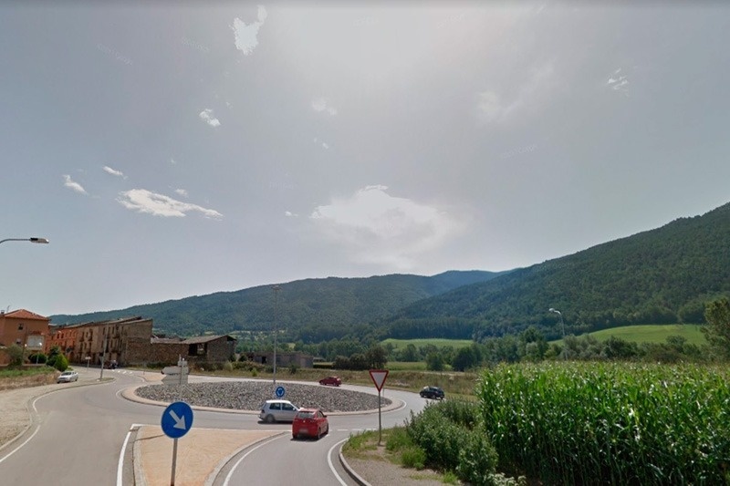 un rond-point avec un panneau bleu et une voiture rouge