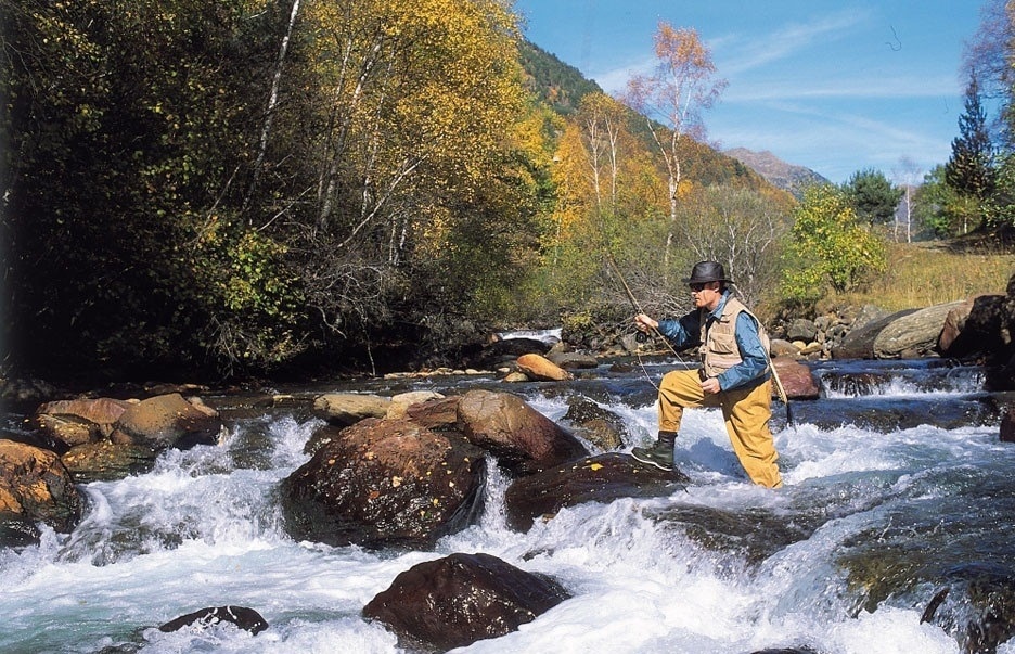 un homme pêche dans une rivière avec une canne à pêche