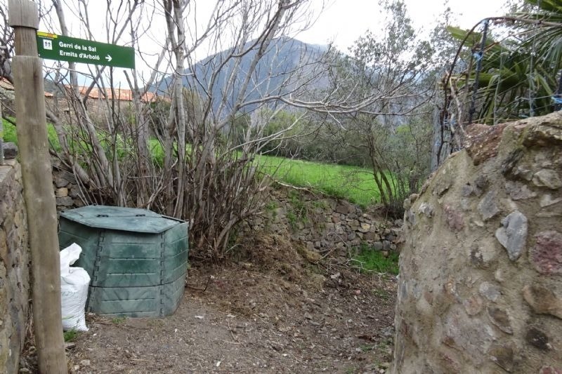 a green sign points the way to a garbage can