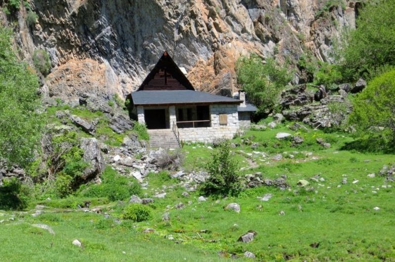 una pequeña casa de piedra en medio de un campo verde