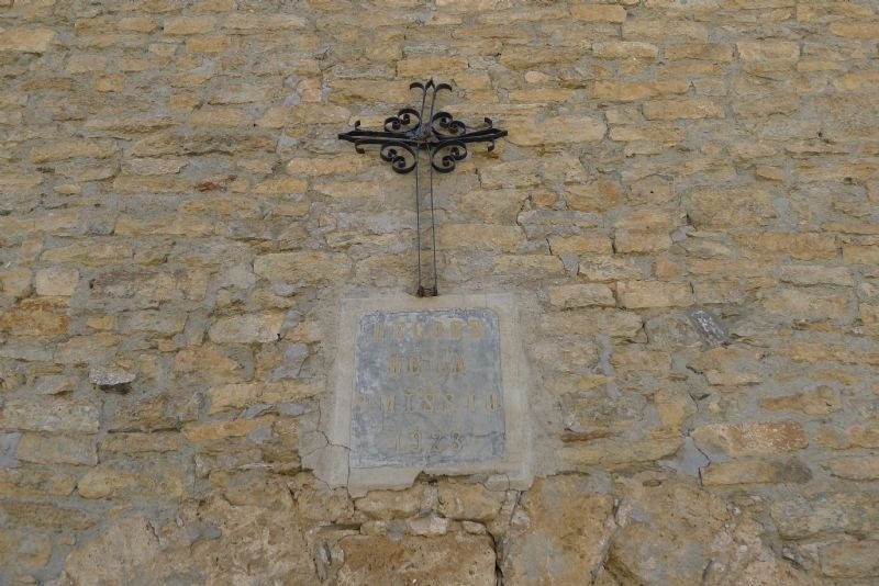 a stone wall with a cross and a plaque that says ' jesus ' on it