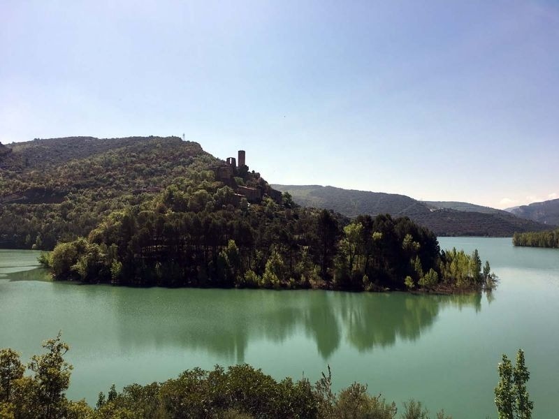 a castle sits on top of a hill overlooking a lake