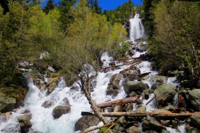 una cascada en la ladera de una montaña rodeada de árboles y rocas