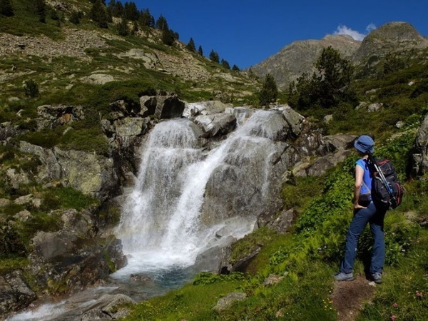 una mujer con una mochila se para frente a una cascada