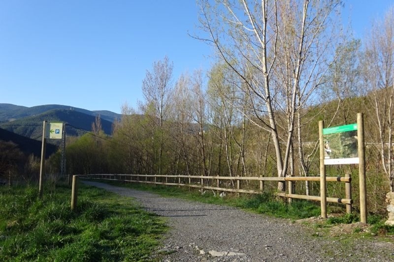 un camino de tierra con una valla de madera y un letrero que dice p.