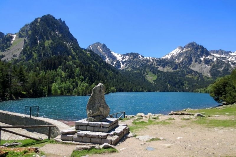 un lago con montañas en el fondo y una roca en primer plano