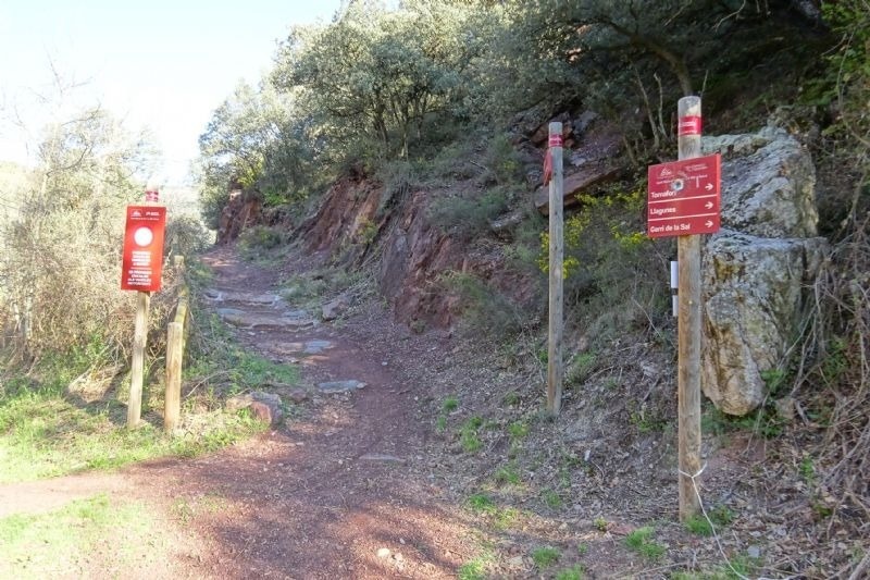 una señal roja que muestra la dirección de un sendero