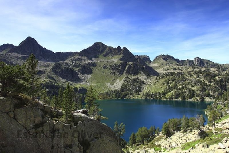 un lago rodeado de montañas y árboles con la palabra esteban oliver al fondo