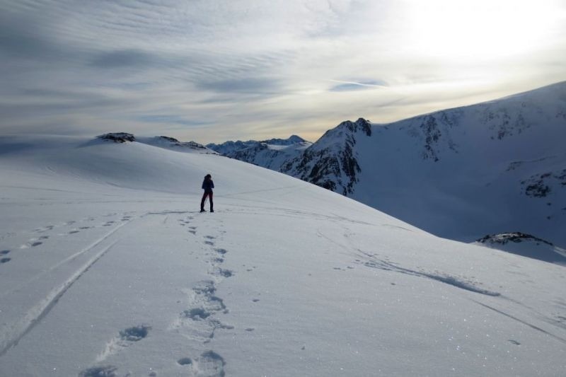 una persona camina a través de la nieve a la ladera d' una montagna