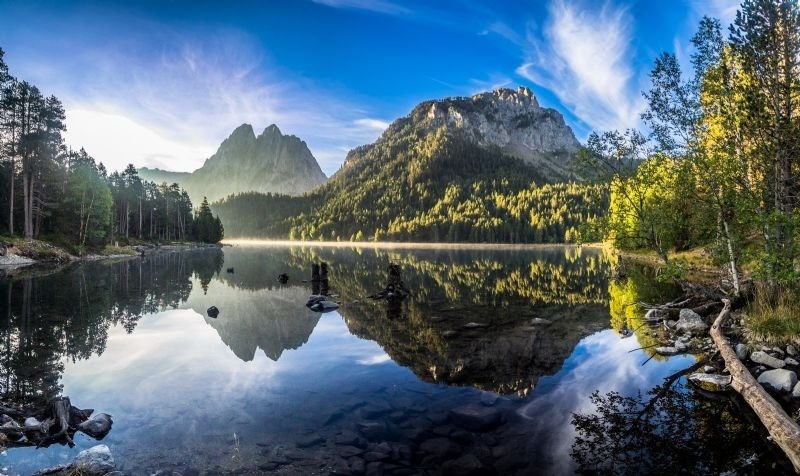 una montaña se refleja en un lago rodeado de árboles