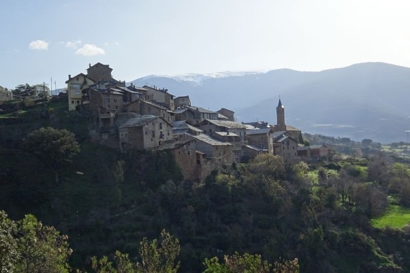 a small village on a hill with mountains in the background