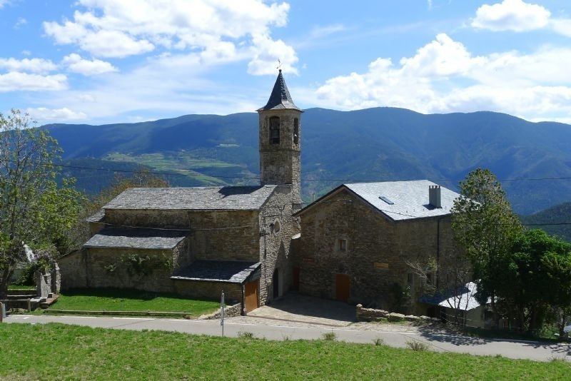 a church with a steeple and mountains in the background