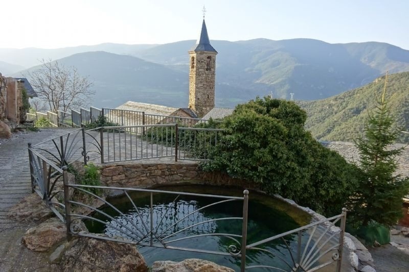 a fence surrounds a pond with a church in the background