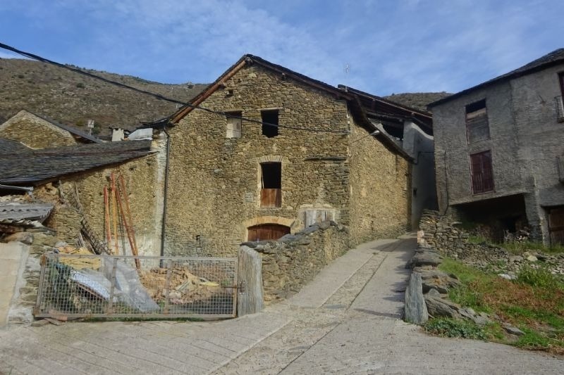 un edifici de pedra a l' esquerra de la carretera