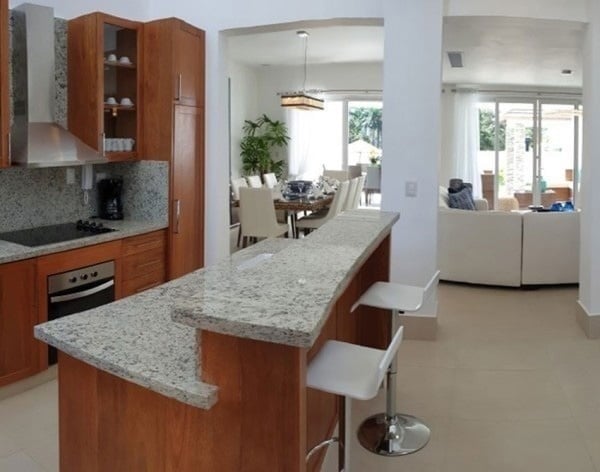 una cocina con un mostrador de granito y sillas blancas