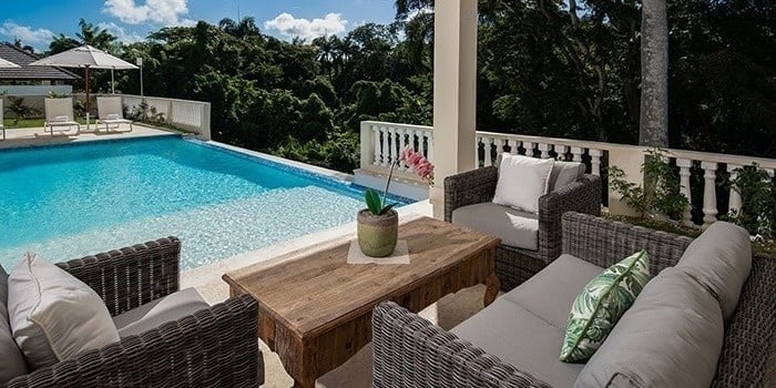 a patio with a couch , chairs and a table next to a swimming pool .