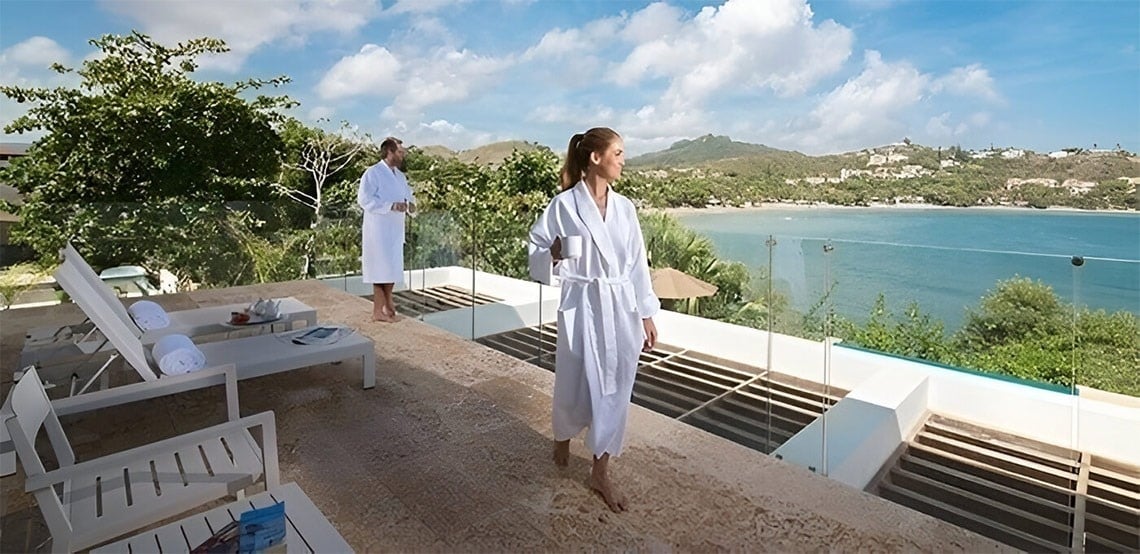 a man and a woman standing on a balcony overlooking the ocean