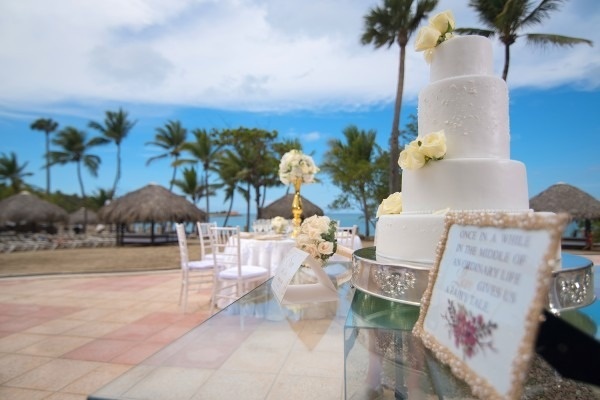 un pastel de bodas blanco se sienta encima de una mesa de vidrio