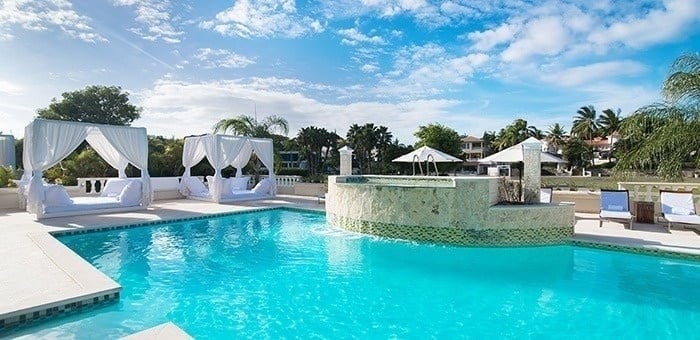 una gran piscina con camas blancas y sillas alrededor .