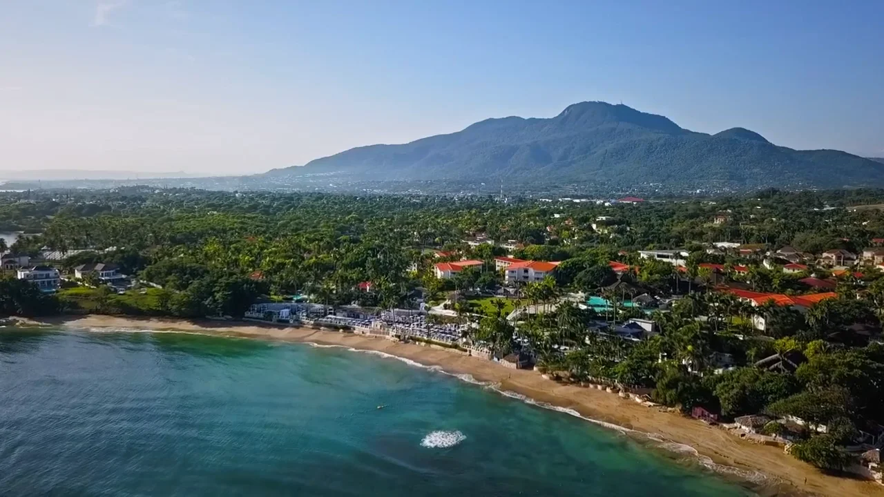 an aerial view of a beach with mountains in the background