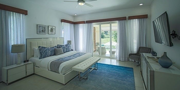 a bedroom with a king size bed , sliding glass doors , a television and a ceiling fan .