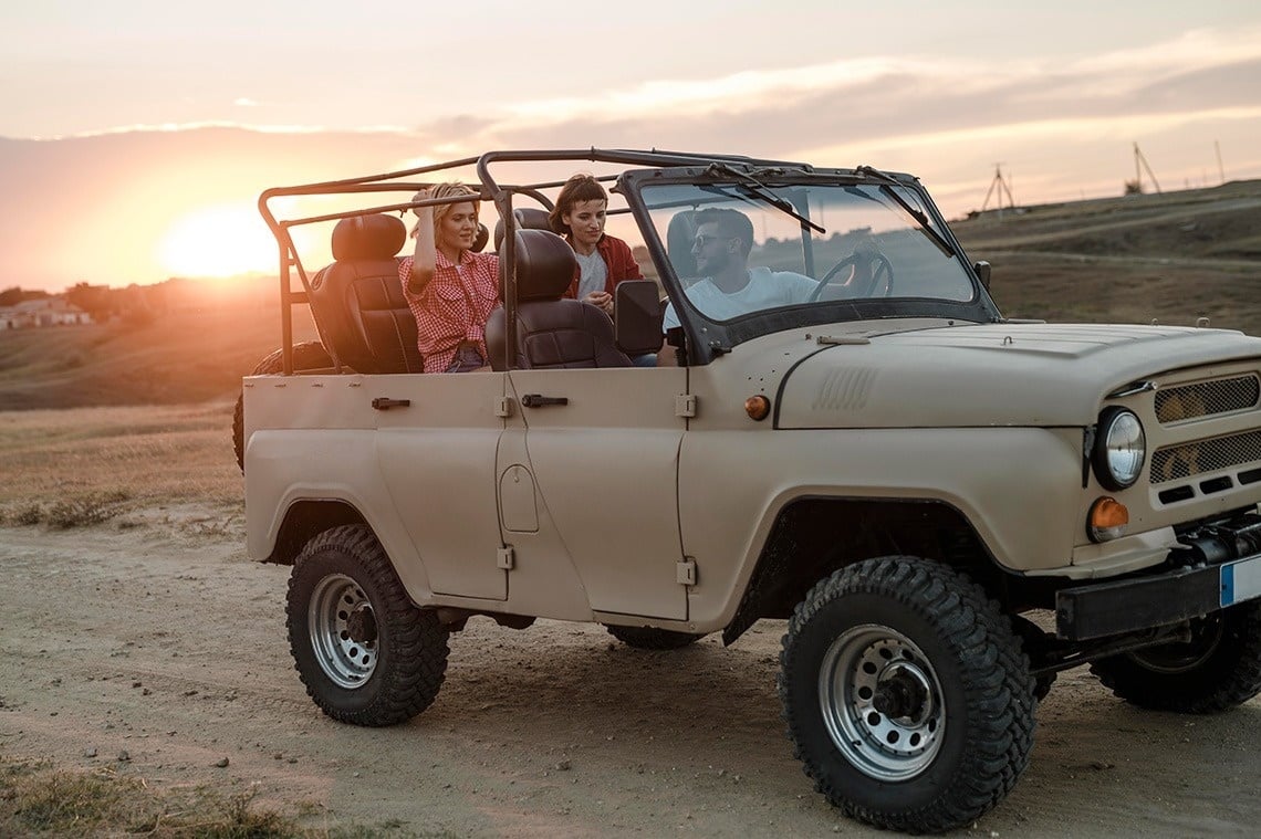 un hombre y una mujer están en un jeep al atardecer