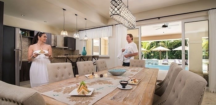 un hombre y una mujer están parados frente a una mesa de comedor .