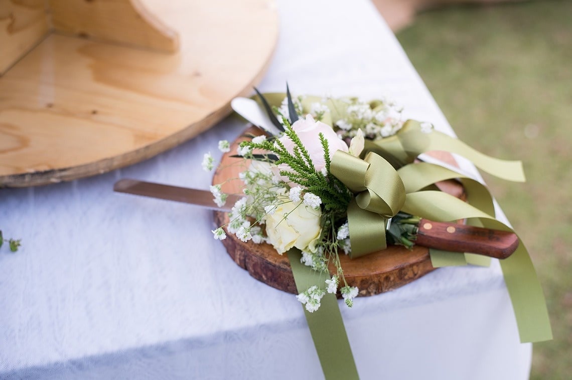 una tabla de cortar de madera con un cuchillo y flores encima