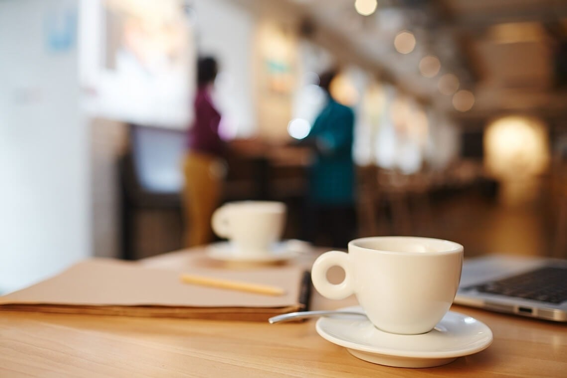 una taza de café se sienta en un plato sobre una mesa de madera