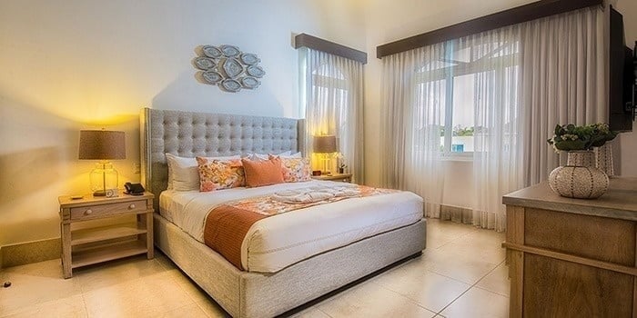 a hotel room with a king size bed , dresser , nightstand , and television .