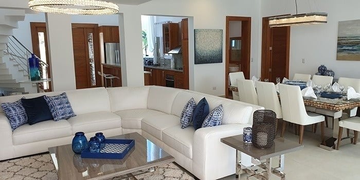 a living room with a white sectional couch and a dining room table .