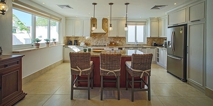 a kitchen with a large island and wicker chairs .