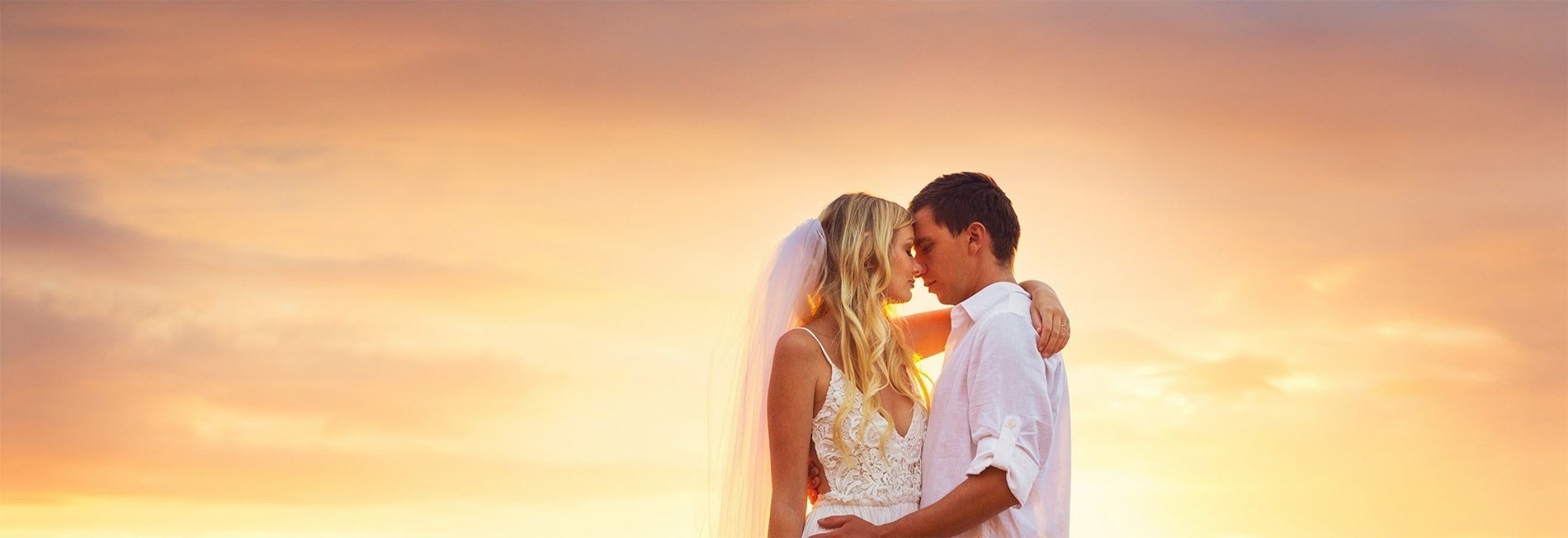 a bride and groom walking on the beach with wedding rings in the foreground