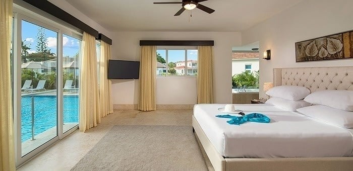 un dormitorio con una cama king size y una piscina al fondo .