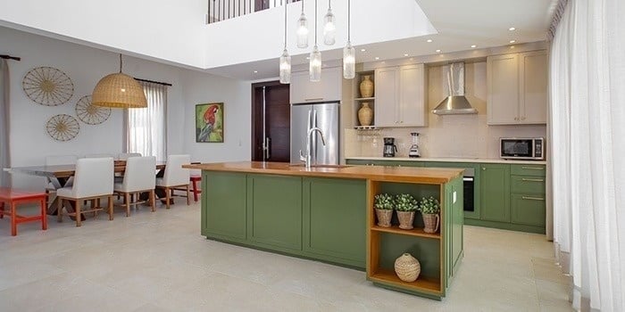 a kitchen with green cabinets and a large island in the middle of the room .