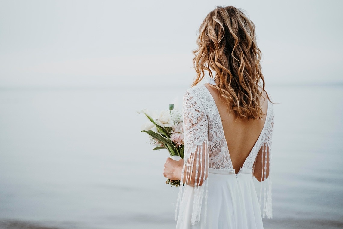 una mujer con un vestido blanco sostiene un ramo de flores