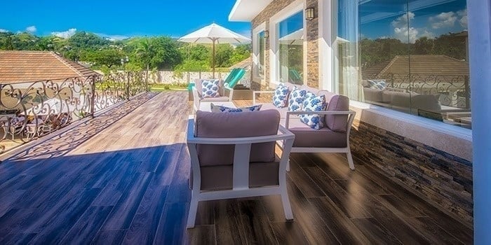 a balcony with chairs , a couch and an umbrella .