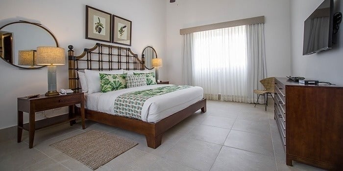a hotel room with a king size bed , dresser , television and mirror .