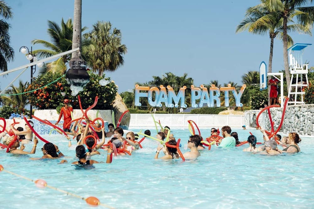 LHVC Resorts: Vibrant pool foam party with balloons and people having fun.