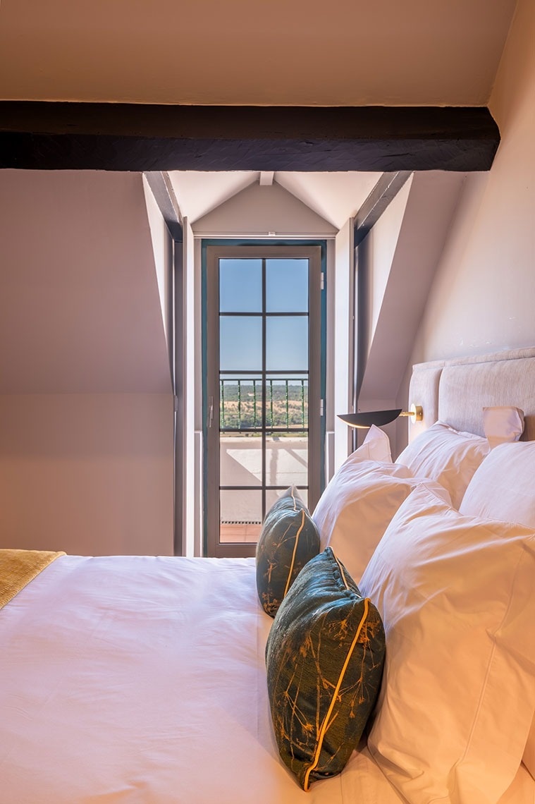um quarto com cama e janela com vista para um terraço