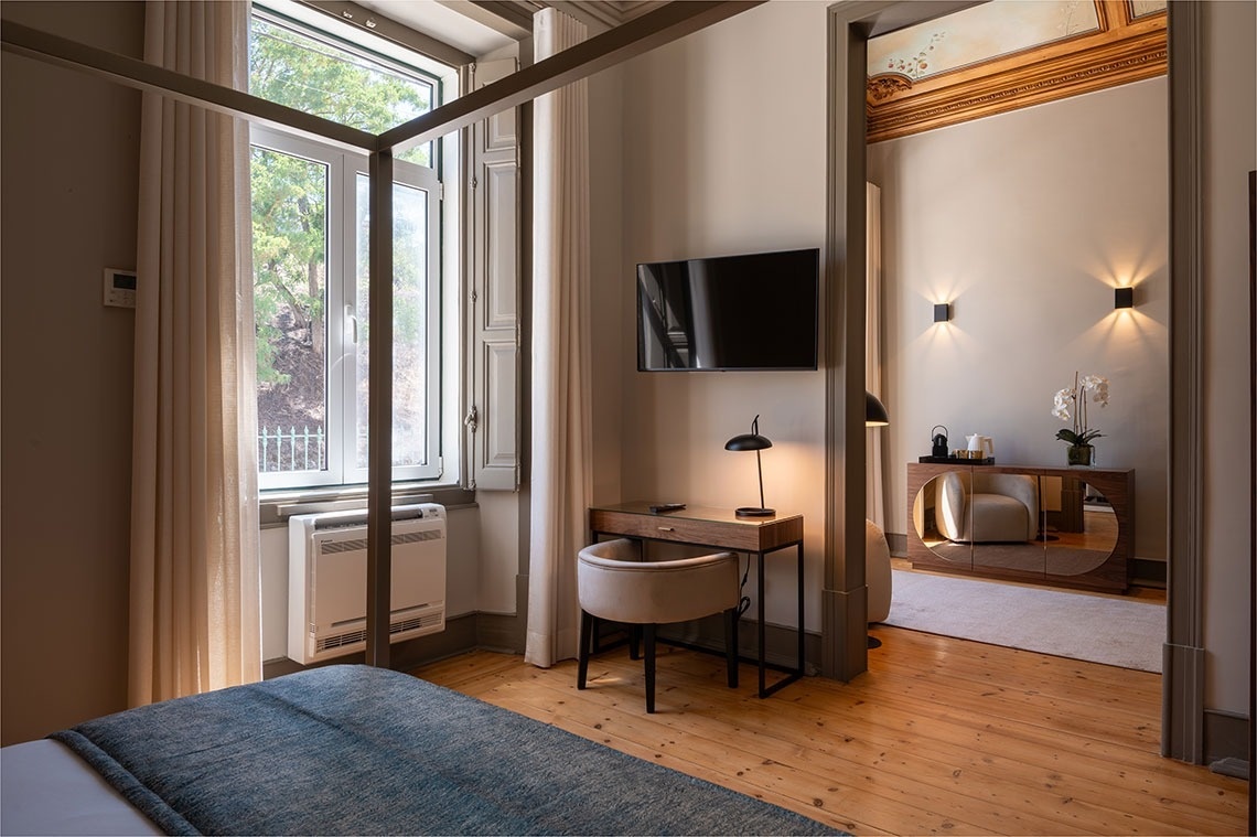 a bedroom with a canopy bed a desk and a flat screen tv