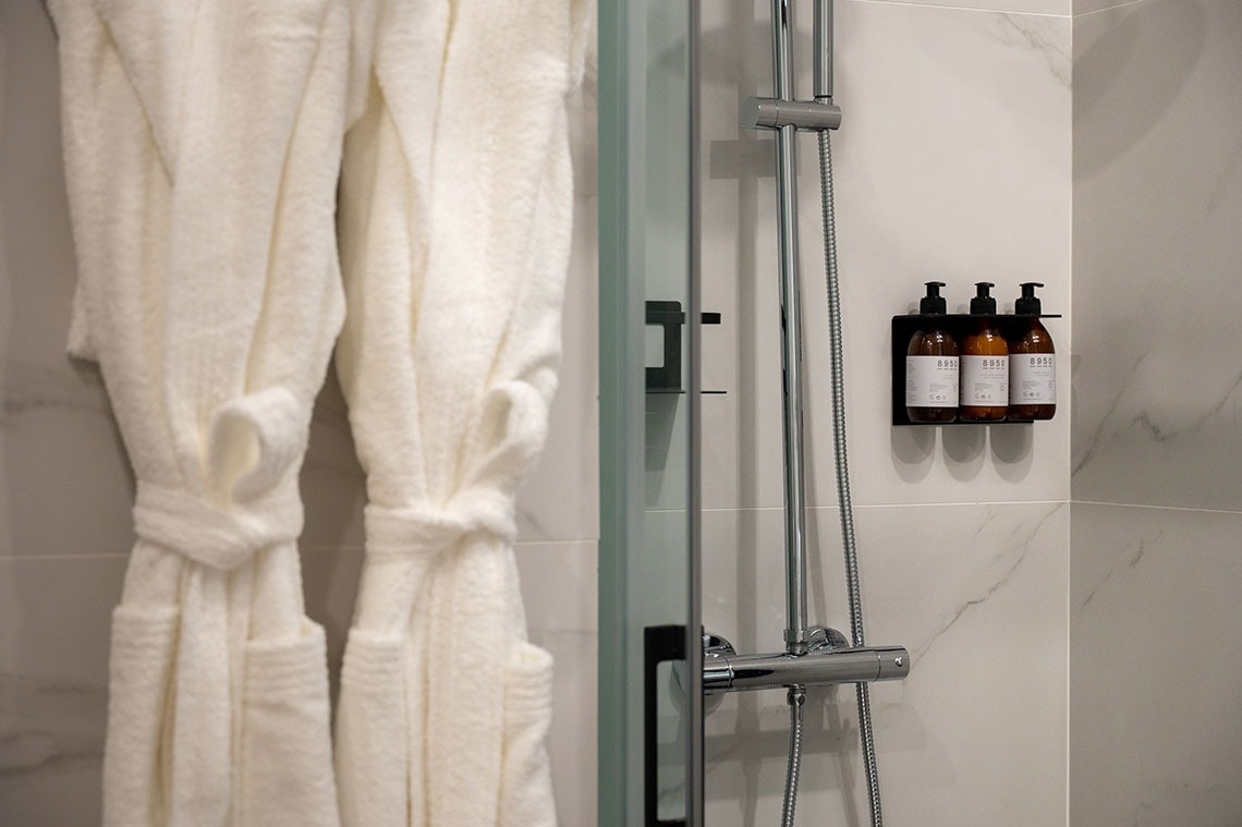 three bottles of lotion are hanging on a wall next to a shower head