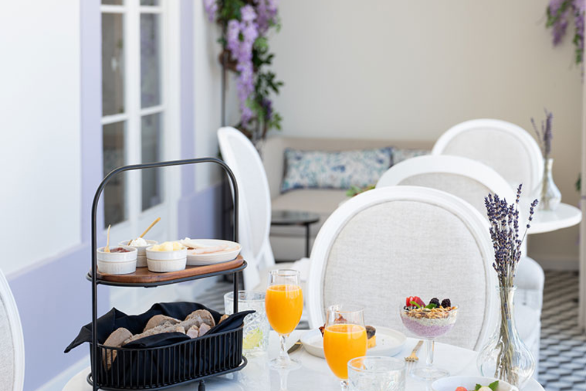 a table with glasses of orange juice and a bowl of cereal