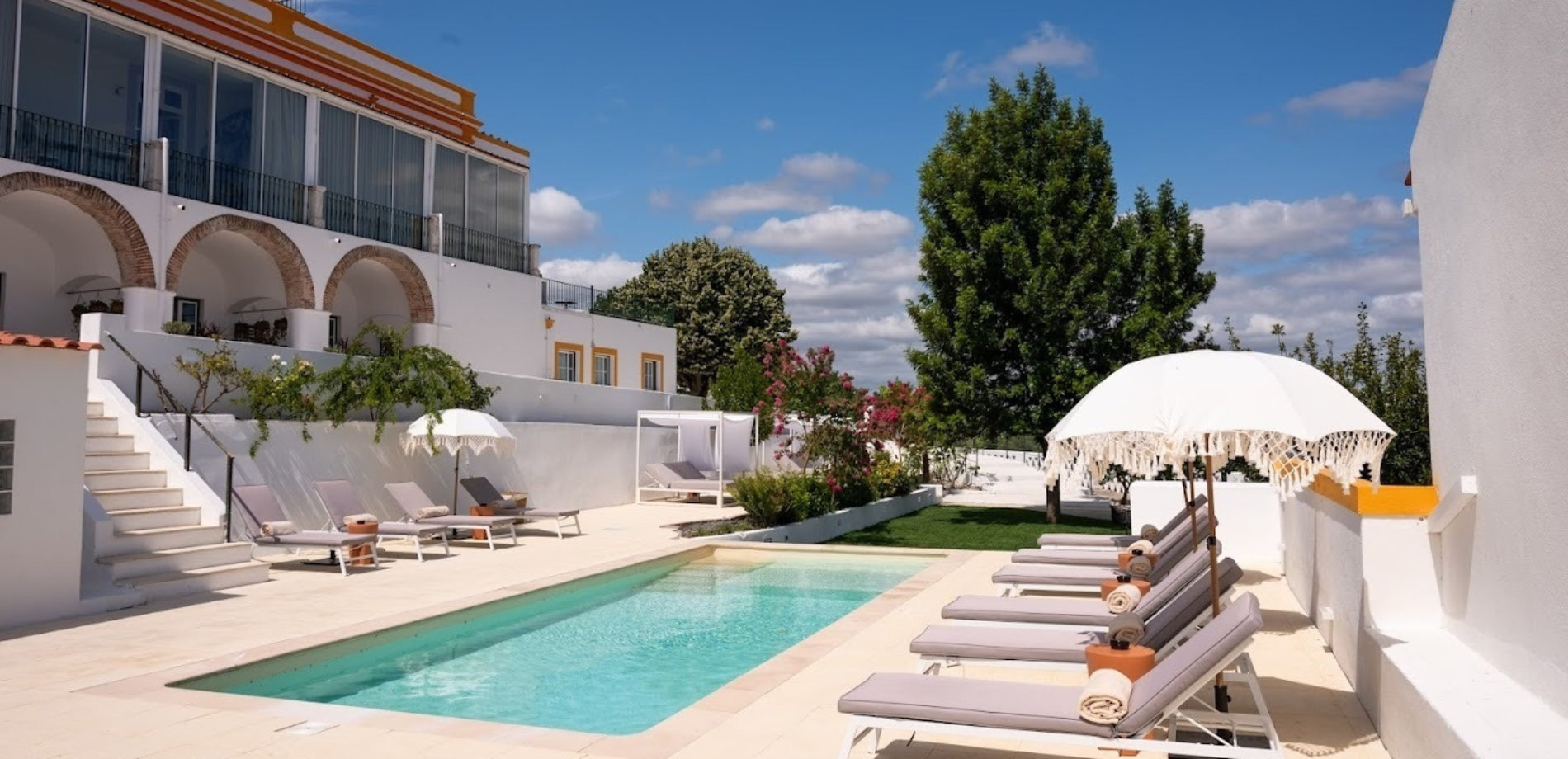 a large swimming pool surrounded by lounge chairs and umbrellas