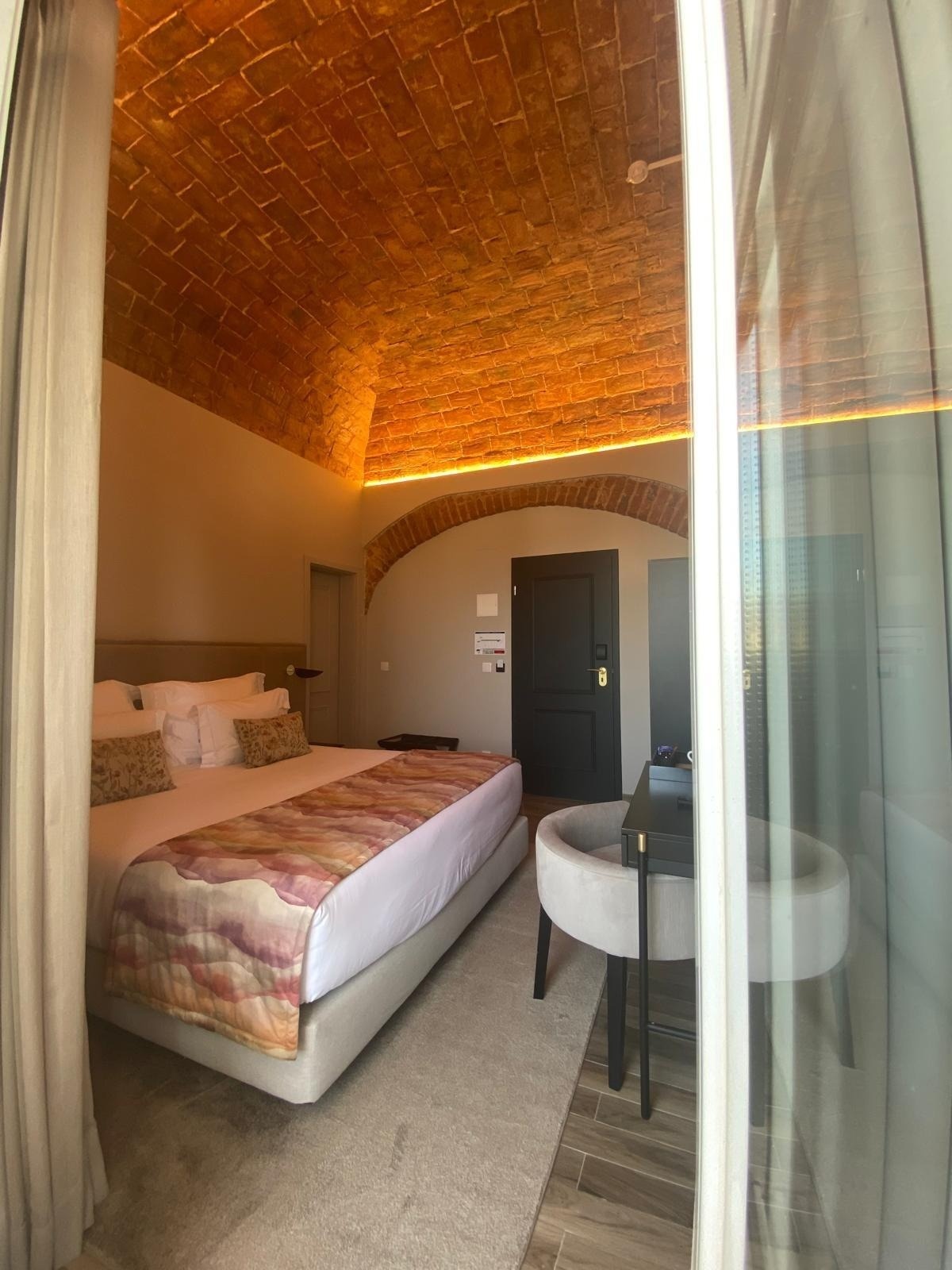 a hotel room with a large bed and a brick ceiling